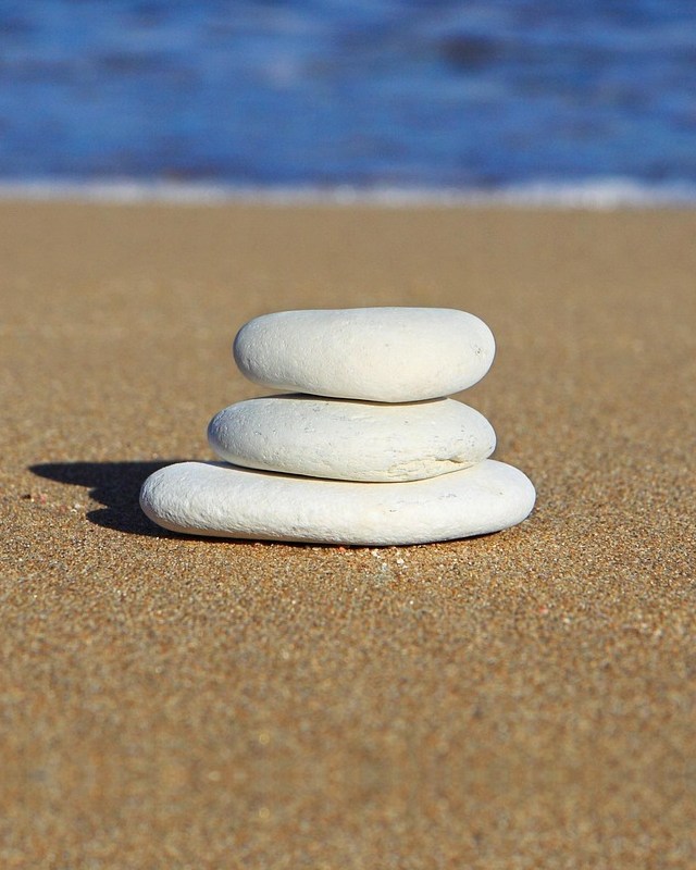 Drei helle Steine, aufeinander gestapelt am Strand.